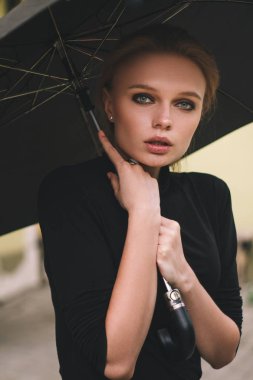 Kız kameraya bakarak şemsiye ile