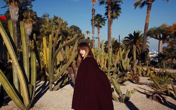 Una joven chica de moda con un abrigo púrpura entre las palmas —  Fotos de Stock