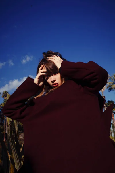 Une jeune fille de la mode dans un manteau violet parmi les paumes — Photo