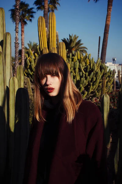 A young fashion girl in a purple coat among the palms — Stock Photo, Image