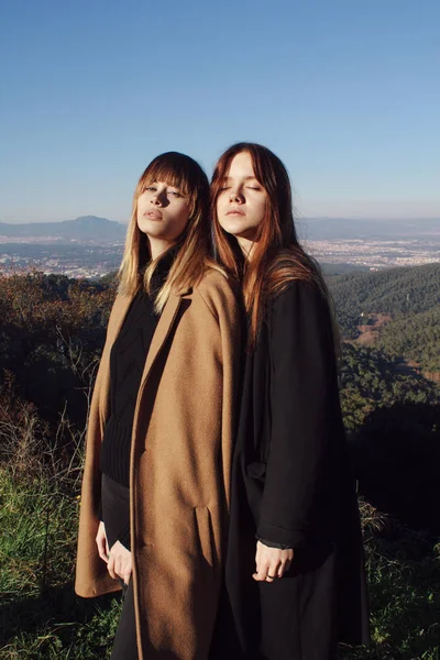 两个女孩站在山上穿着时尚大衣 — 图库照片