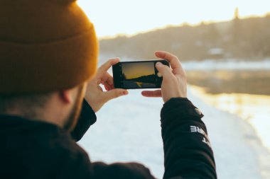 Nehir doğası kış manzarasının fotoğrafını çeken bir adam..