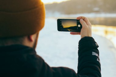 Nehir doğası kış manzarasının fotoğrafını çeken bir adam..
