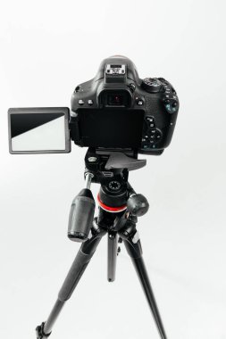 Üç ayaklı arka planda Lcd ekranlı bir fotoğraf makinesi. Beyaz arkaplanda stüdyo görüntüsü