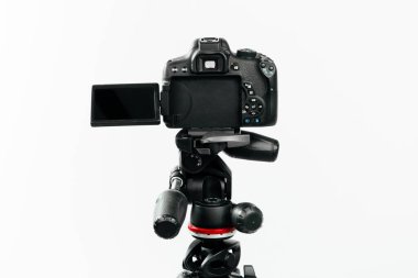 Üç ayaklı arka planda Lcd ekranlı bir fotoğraf makinesi. Beyaz arkaplanda stüdyo görüntüsü