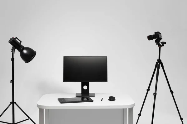 Fotograf miejsce pracy w studiu fotograficznym ze sprzętem oświetleniowym. Kamera na statywie. Komputer na biurku. Miejsce pracy projektanta. — Zdjęcie stockowe