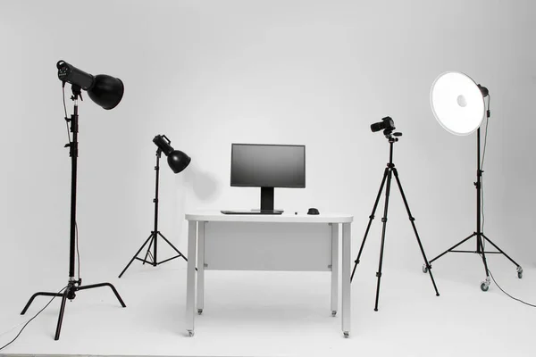 Fotógrafo local de trabalho em estúdio de fotografia com equipamento de iluminação. Câmera no tripé. Computador PC na mesa. Local de trabalho do designer . — Fotografia de Stock