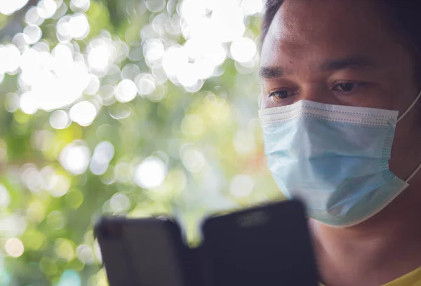 Cerrahi maske takan bir adam evde telefonla çalışıyor..