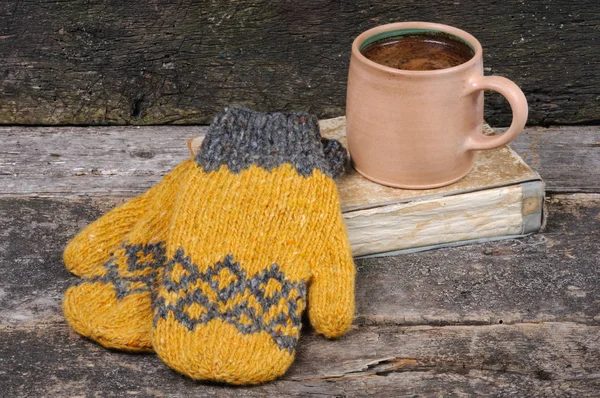 Sarı örme eldiven el yapımı kitap ve bir fincan kahve yalan. Önden Görünüm.