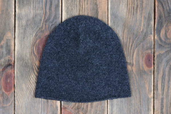 Handmade knitted hat. Wooden background. View from above.