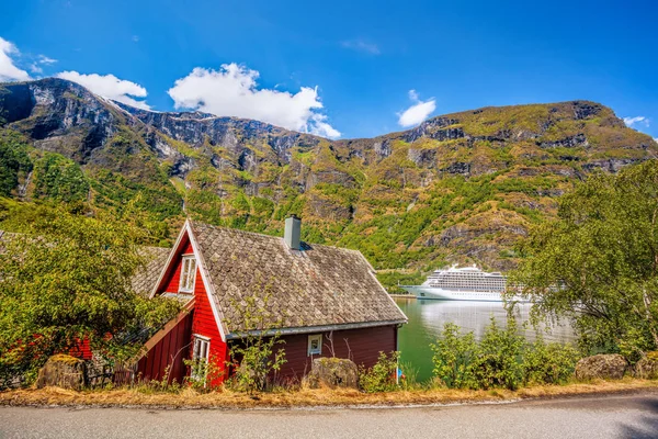 Casa de campo vermelha contra navio de cruzeiro no fiorde, Flam, Noruega — Fotografia de Stock
