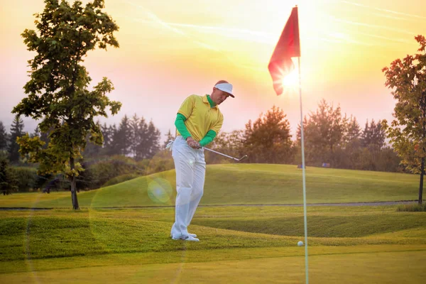 Человек играет в гольф против яркого заката — стоковое фото