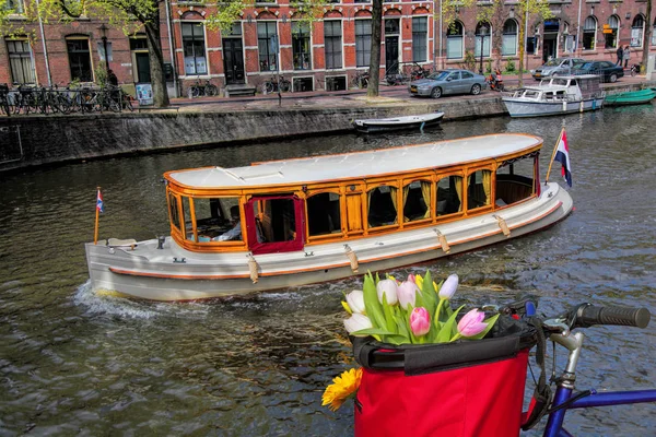 Berühmte amsterdam mit korb mit bunten tulpen gegen boot in holland — Stockfoto