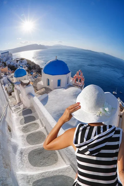 Frau mit Hut beobachtet oia-Dorf auf Santorini-Insel in Griechenland — Stockfoto