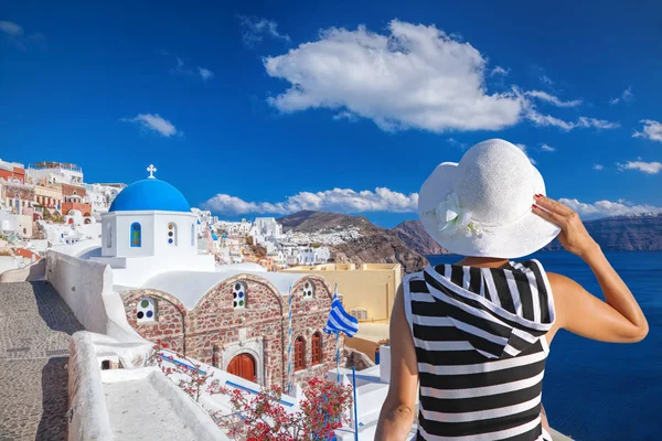 Kobieta w kapeluszu oglądania miejscowości Oia, na wyspie santorini w Grecji — Zdjęcie stockowe