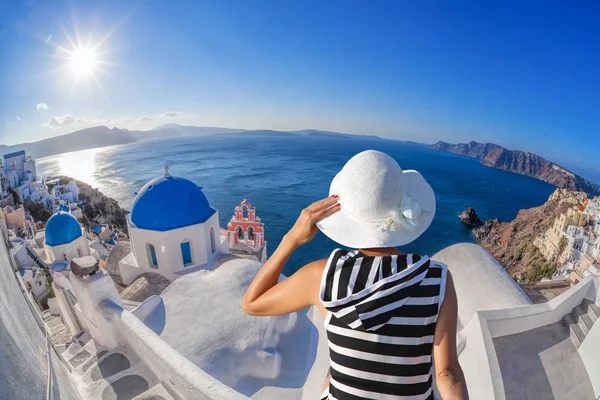 Mujer con sombrero viendo el pueblo de Oia en la isla Santorini en Grecia — Foto de Stock