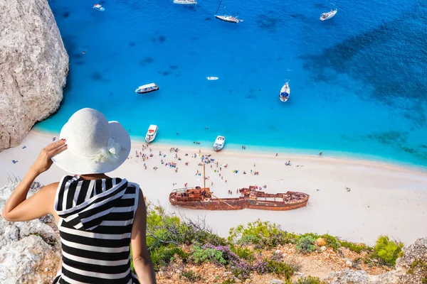 Mulher com chapéu assistindo Navagio praia com naufrágio na ilha de Zakynthos, na Grécia — Fotografia de Stock