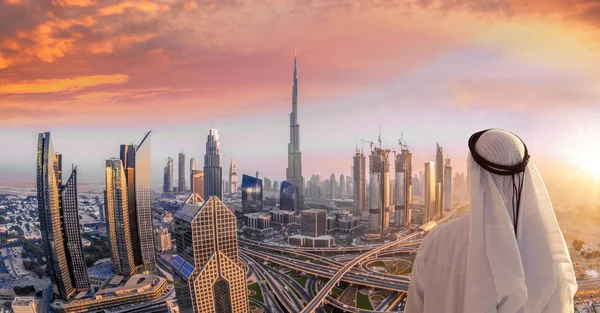 Homem árabe assistindo paisagem urbana de Dubai com arquitetura futurista moderna em Emirados Árabes Unidos . — Fotografia de Stock