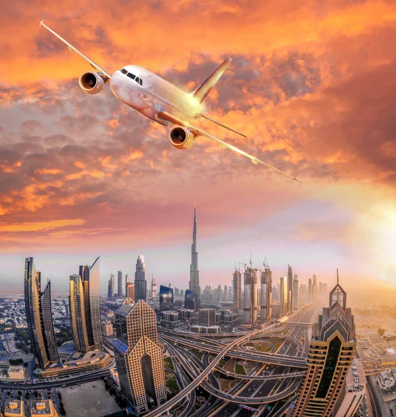 Avião está voando sobre Dubai contra o pôr do sol colorido em Emirados Árabes Unidos — Fotografia de Stock