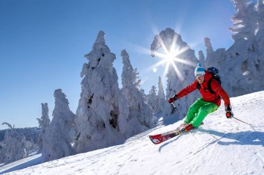 Yokuş aşağı mavi gökyüzü karşı yüksek dağlarda kayak kayakçı