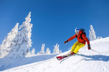 Yokuş aşağı mavi gökyüzü karşı yüksek dağlarda kayak kayakçı
