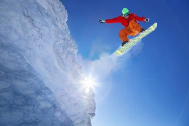 Mavi gökyüzüne atlayan snowboardcu