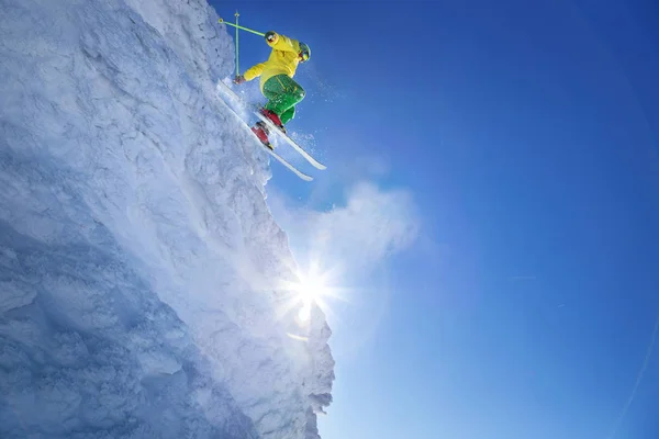Лыжник прыгает с голубого неба со скалы — стоковое фото