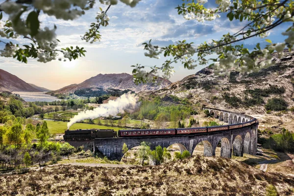 Glenfinnan Ferrocarril Viaducto en Escocia con el tren de vapor jacobita contra la puesta de sol sobre el lago —  Fotos de Stock