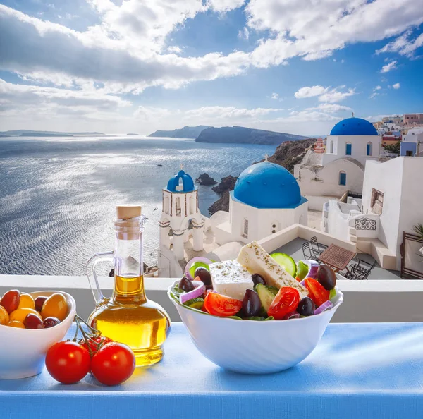 Greek salad against famous church in Oia village, Santorini island in Greece — Stock Photo, Image