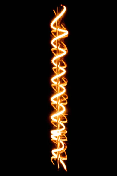 El filamento resplandeciente de una bombilla - fondo negro - macrofotografía — Foto de Stock