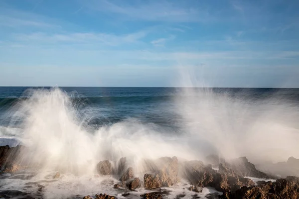 Vagues s'écrasant sur des rochers au bord de la côte - photographie à longue exposition — Photo