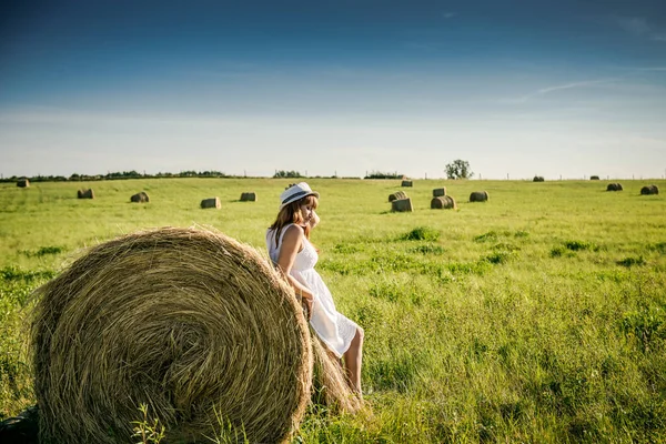 Güzel kız işten sonra dinleniyor. Sahada samanlı bir kız. Bir tarlada saman demetinin yanında bir kadın. Kırsal yaşam. Köyde tatil.