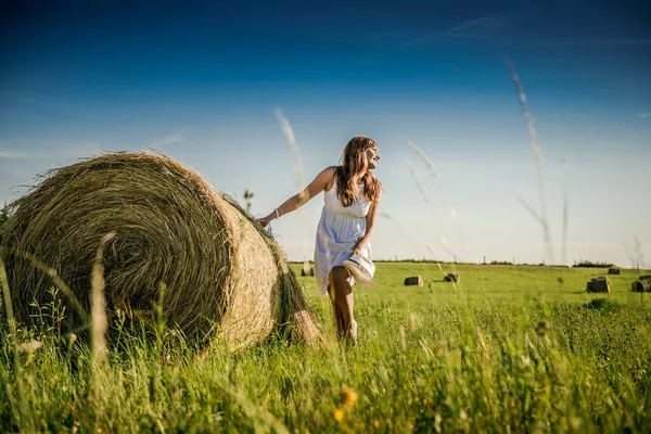 Güzel kız işten sonra dinleniyor. Sahada samanlı bir kız. Bir tarlada saman demetinin yanında bir kadın. Kırsal yaşam. Köyde tatil.