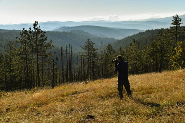 Photographer shooting hills on Tara mountain Serbia. Beautiful sunny day in high mountain. Far away blue hills in the backgroung.