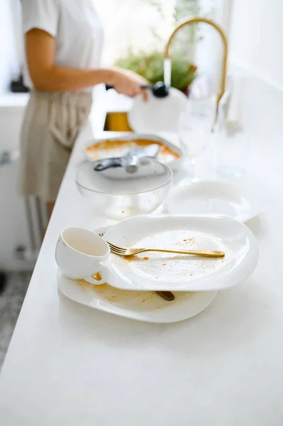 Hermosa joven sonriente lavando los platos en la moderna cocina blanca. — Foto de Stock