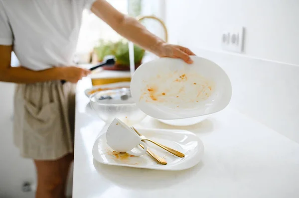 Hermosa joven sonriente lavando los platos en la moderna cocina blanca. — Foto de Stock