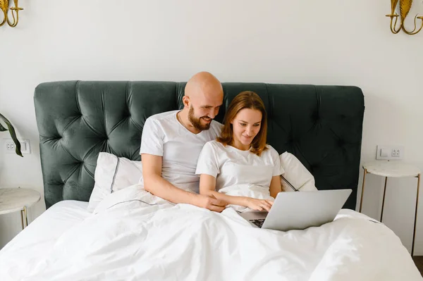 Jovem casal usando laptop juntos na cama — Fotografia de Stock