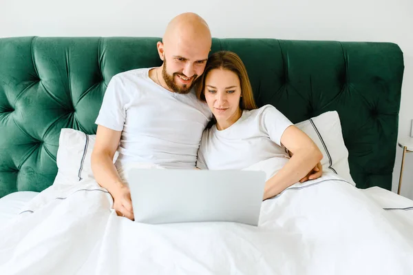 Jovem casal usando laptop juntos na cama — Fotografia de Stock