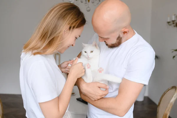 Um jovem casal segurar um gato branco em seus braços — Fotografia de Stock
