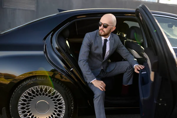 Business man in suit opening black car door