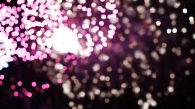 Stok videosu 4K. Gerçek havai fişek arka planının kusursuz döngüsü. Bokeh lambalı gerçek altın rengi havai fişeklerin soyut bulanıklığı. Yeni yıl arifesi havai fişekleri