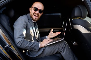 İşadamı, yönetici arabasının arka koltuğunda dizüstü bilgisayarla çalışıyor. İş kavramı, başarı, seyahat, lüks.