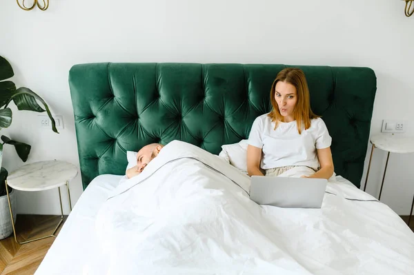Jeune couple utilisant ordinateur portable ensemble au lit — Photo
