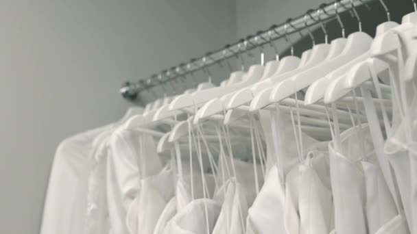 Bröllopssalong. Bröllopsklänningar hänger på hängare. Många klänningar. — Stockvideo