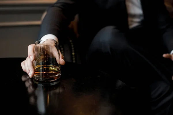 Hombre con traje sostiene un vaso con whisky — Foto de Stock