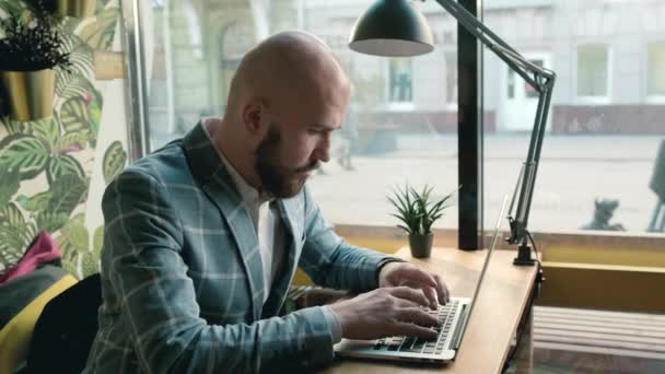 Homem careca em uma jaqueta funciona em um computador — Vídeo de Stock