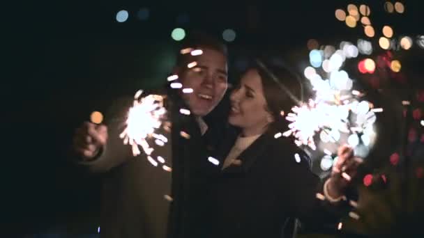 Foco seletivo de sparklers em mãos de jovem casal desfrutando de férias ao ar livre — Vídeo de Stock