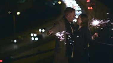 Mutlu çift birbirine bakar ve sarılır ve ellerinde maytap tutarlar.