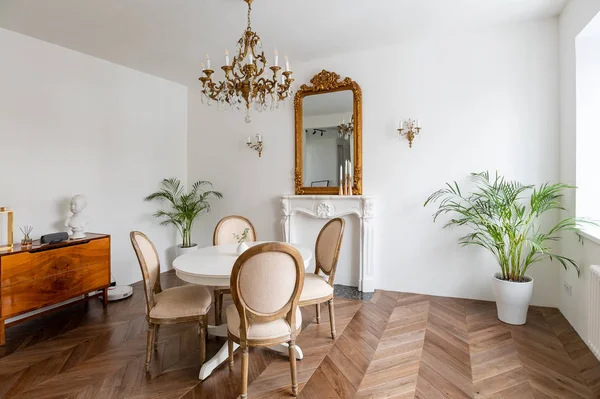 Hvid stue med klassisk indretning, spejl, pejs, spisebord - Stock-foto
