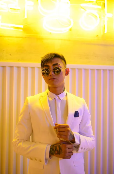 Mladý asijský muž v bílém obleku na pozadí neonových světel — Stock fotografie